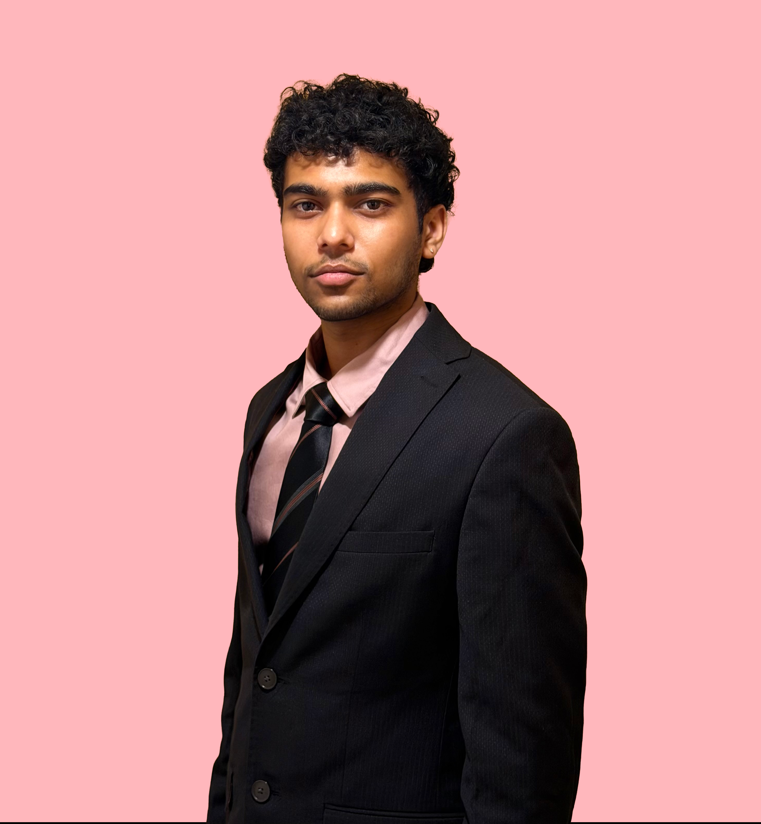Aditya Chandrasekar wearing a dark suit against a pink background